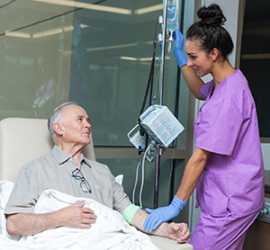 Health care provider caring for man having infusion treatment.